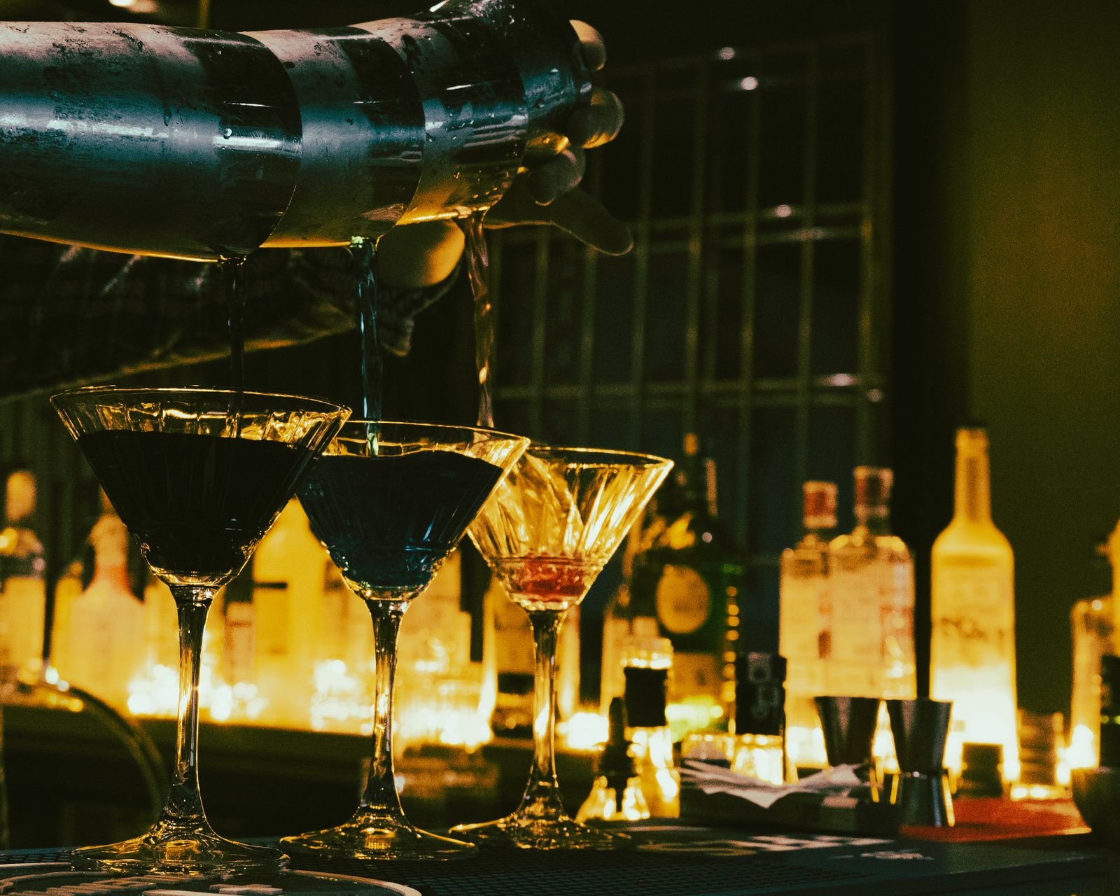 Martini glasses being filled on a candlelit bar